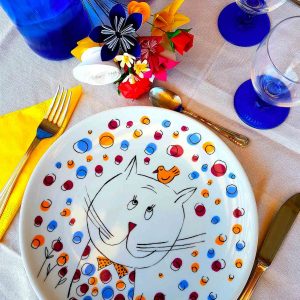 piatto con disegnato un gatto colorato appoggiato su una tavola bianca